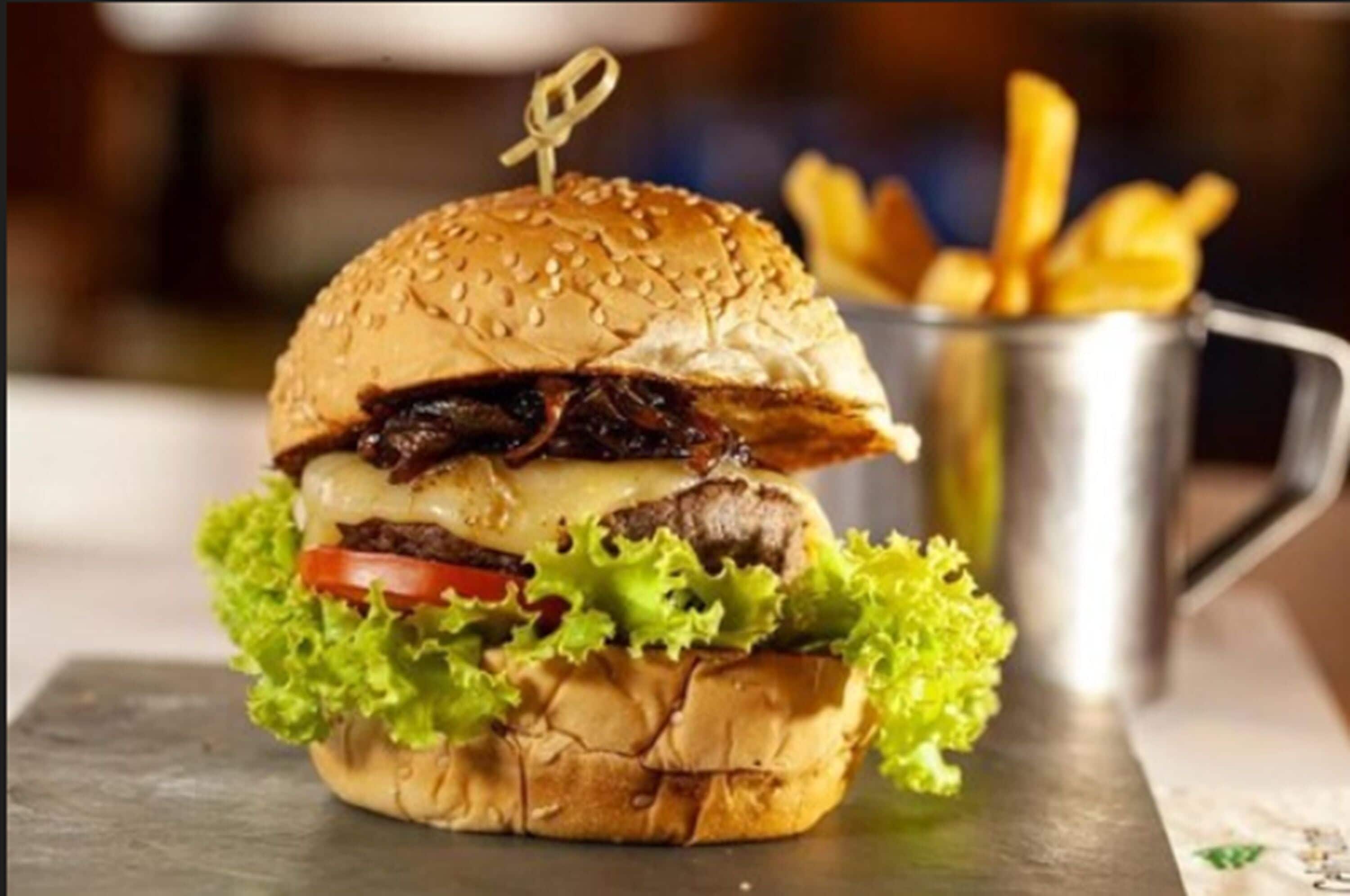 A burger with fries on a metal tray.