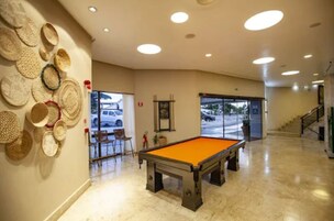 A billiards table in a well-lit room with a wall decorated with woven baskets.