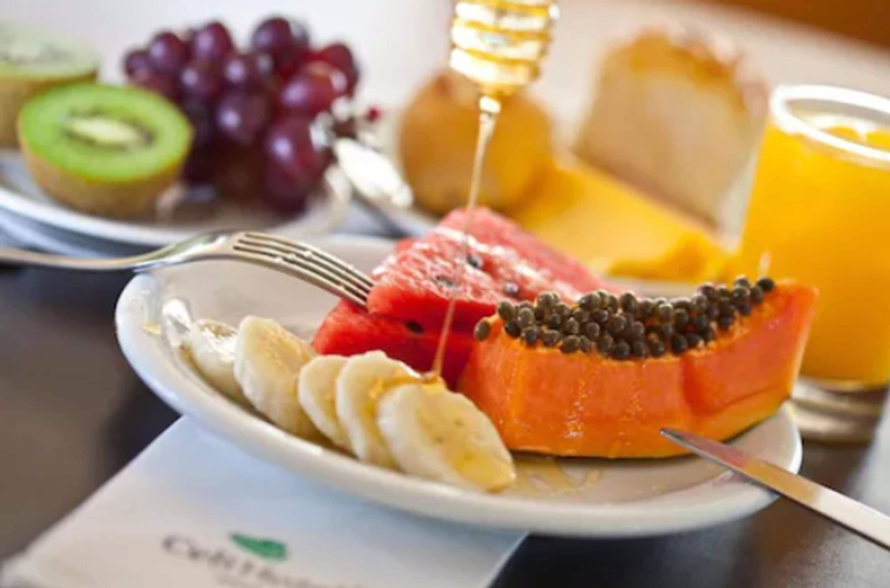 A breakfast plate with sliced bananas, watermelon, papaya, and grapes.
