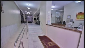 Un vestíbulo de hotel con suelo de mármol, un mostrador de recepción y una escalera que conduce a otras zonas.