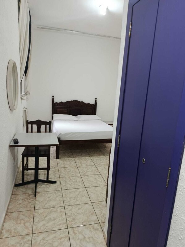 Un dormitorio con cama, una mesita y un armario.
