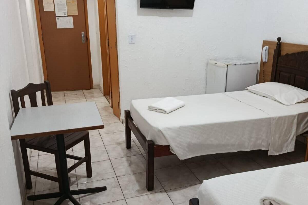 A small, clean room with a bed, a desk, and a TV mounted on the wall.