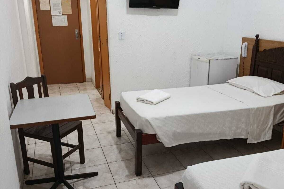 A small, clean room with a bed, a desk, a chair, and a television on the wall.