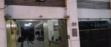 Entrada de un hotel con puerta de cristal, una escalera que conduce al interior y un letrero con el nombre del hotel.