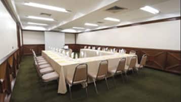 A conference room with a long table, chairs, and a carpeted floor.
