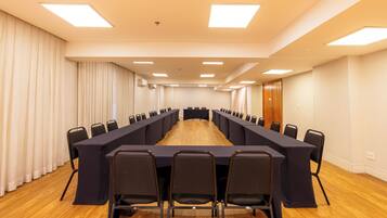 A conference room with a long table, chairs, and a wooden floor.