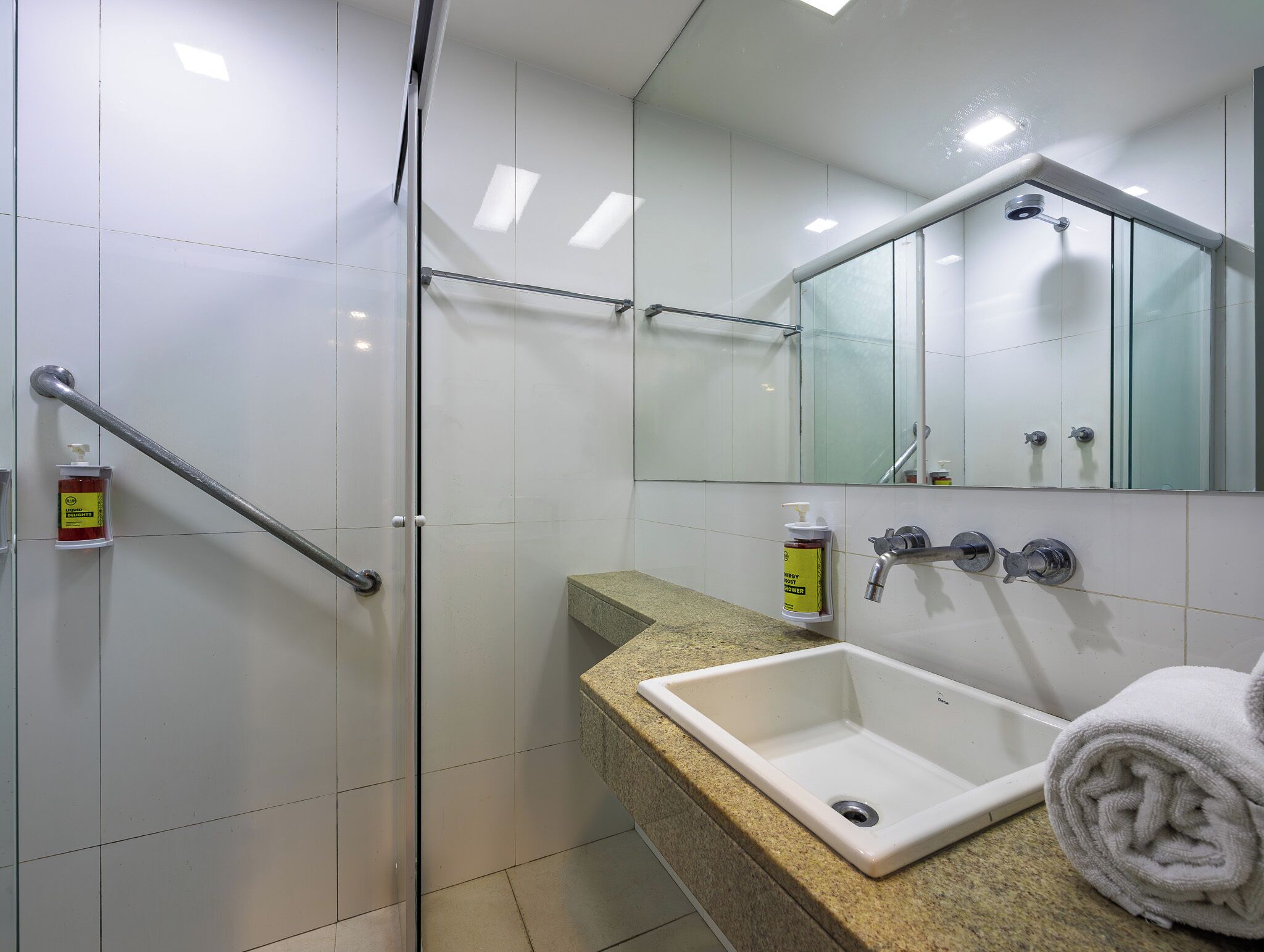 Une salle de bain dotée d’une douche à parois de verre, d’un lavabo avec un plan de travail en granit et d’un miroir au-dessus du lavabo.