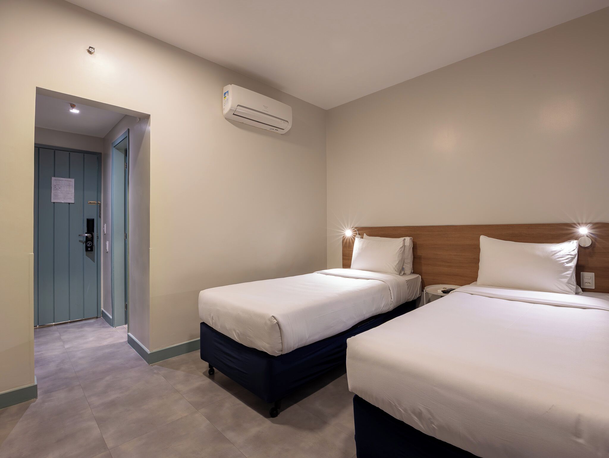 Une chambre d’hôtel avec deux lits, une porte et un appareil de climatisation.