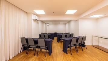 Un salón de conferencias con una mesa larga, sillas y un separador de vidrio.