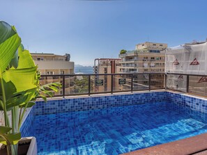 Une piscine sur le toit offrant une vue dégagée sur l’océan et les bâtiments en arrière-plan.