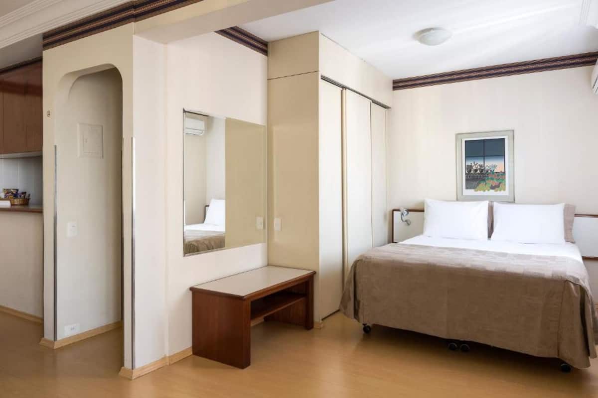 Een slaapkamer met een bed, nachtkastje, spiegel en kledingkast.