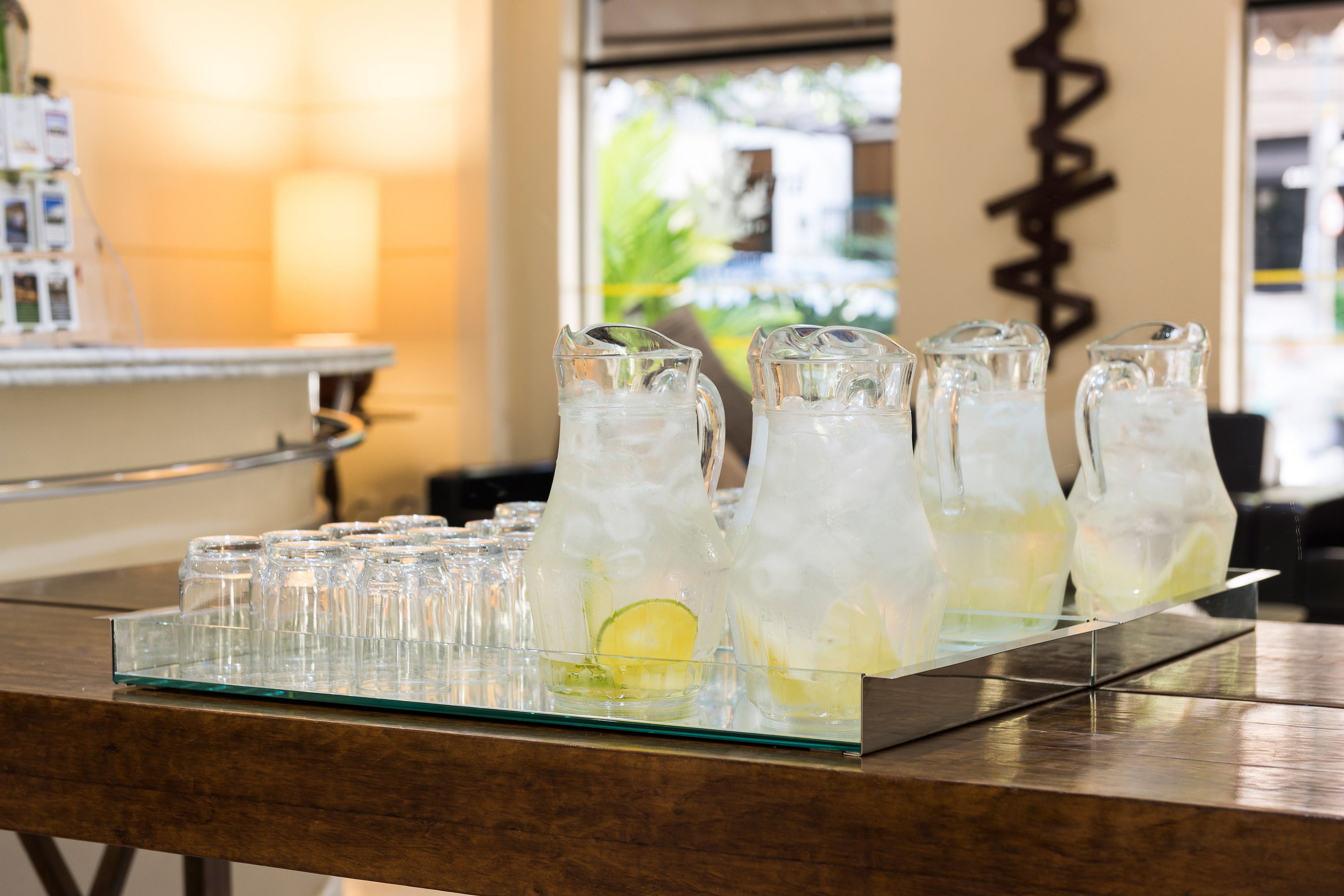 A bar area with multiple pitchers of iced drinks, a glass tray, and a bar counter.
