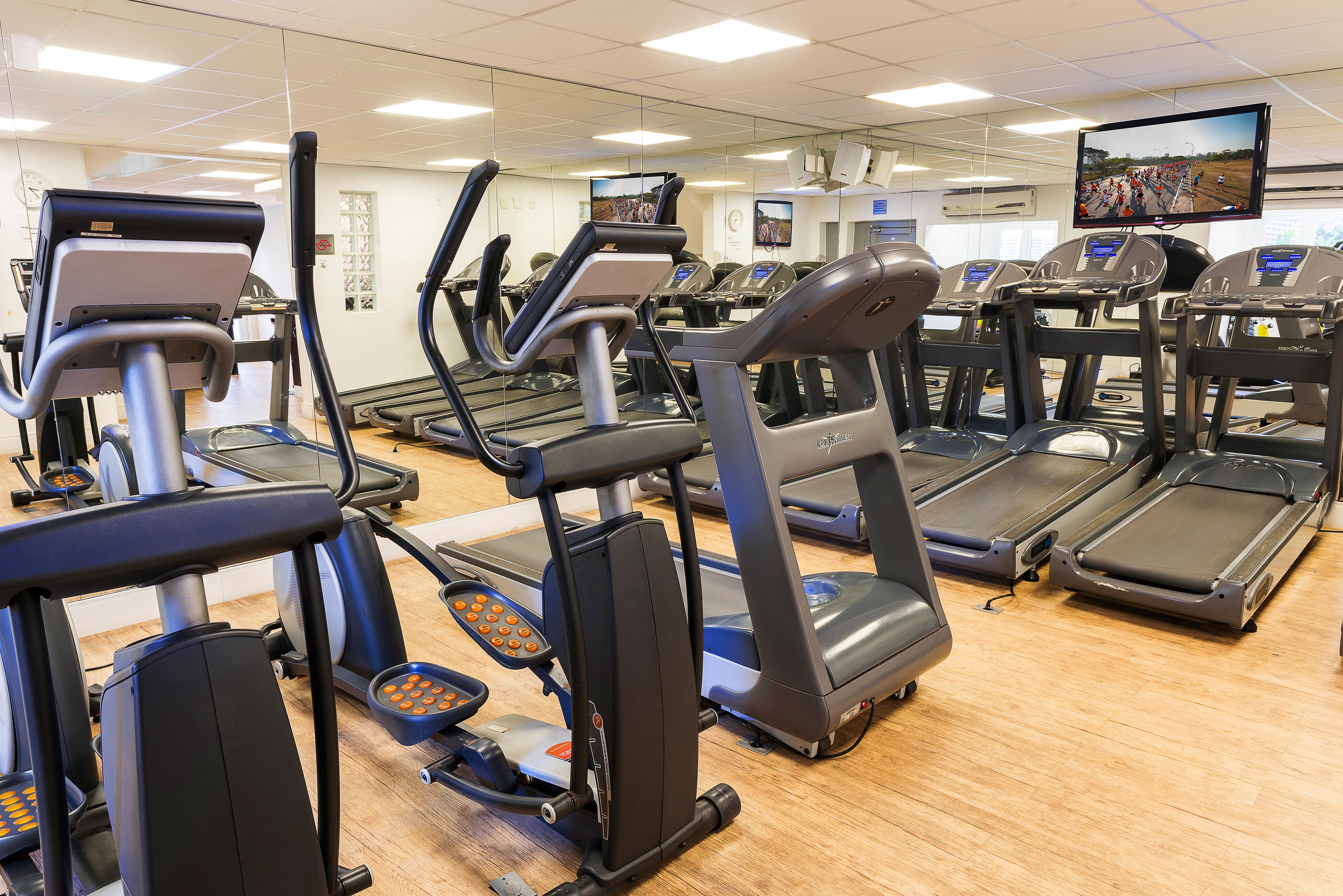 Une salle de sport équipée de plusieurs tapis de course et de plusieurs appareils de musculation elliptique.