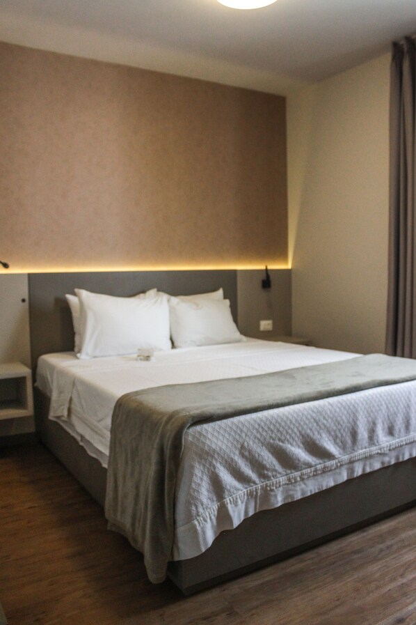 A hotel room with a large bed, a bedside table, and a wall-mounted light fixture. - Central Park Jardins (São Paulo)