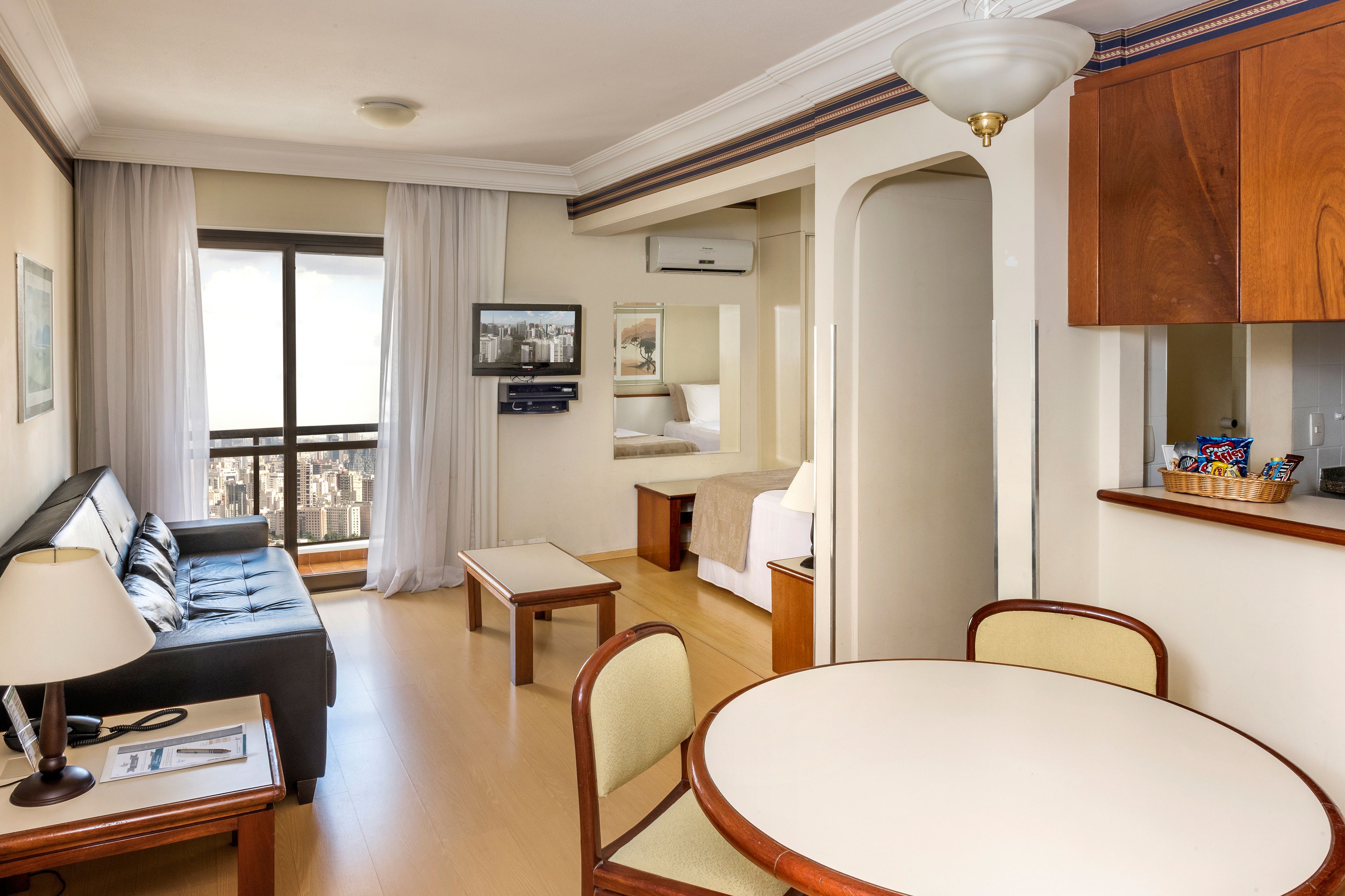 Una habitación de hotel con balcón, sofá, mesa de comedor y cama.