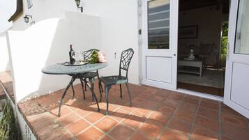 A patio with a table and chairs, a door leading to an interior room, and a brick wall with a window.