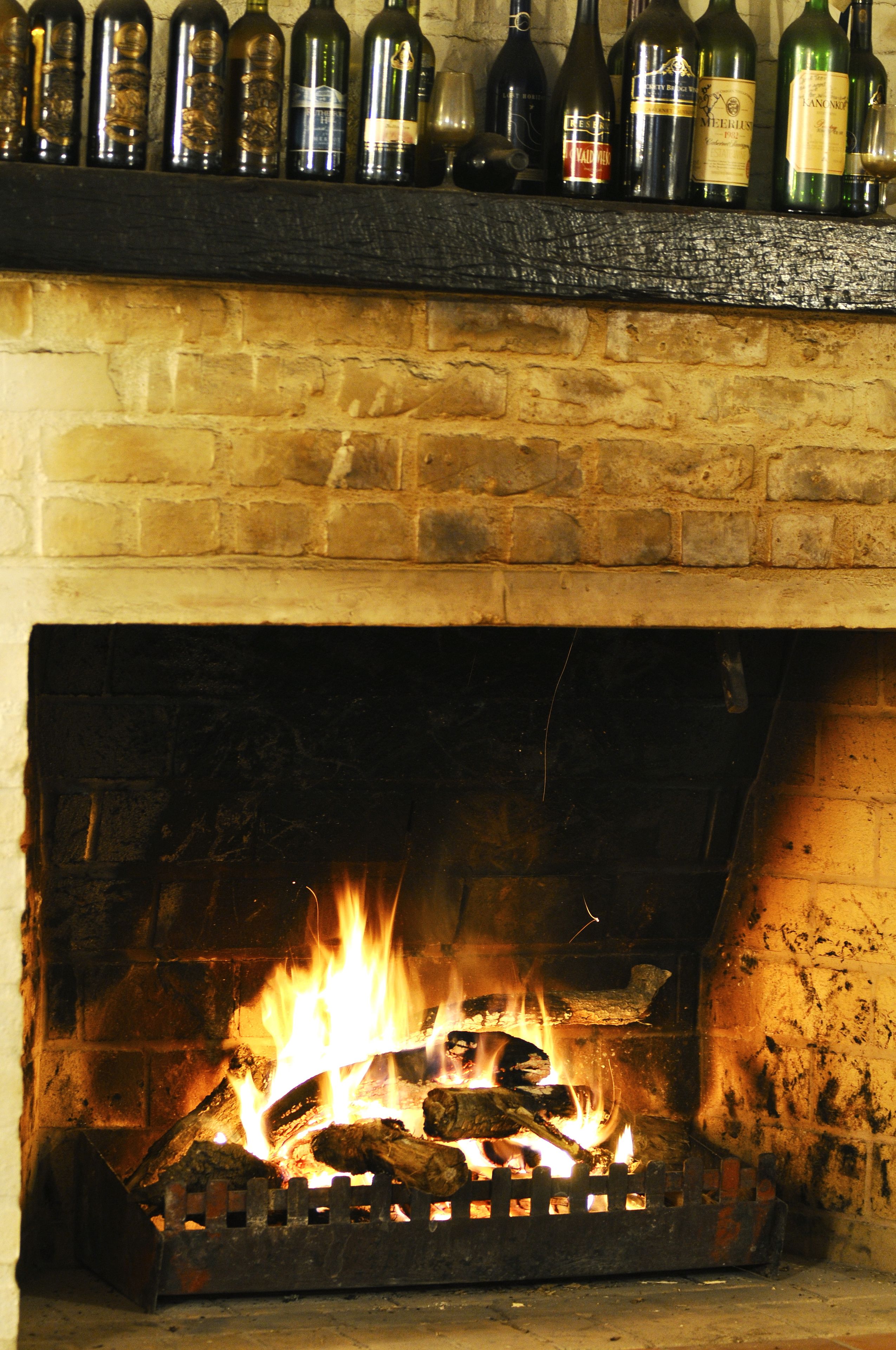 Une cheminée avec un feu qui crépite à l’intérieur, entourée d’un mur de briques.