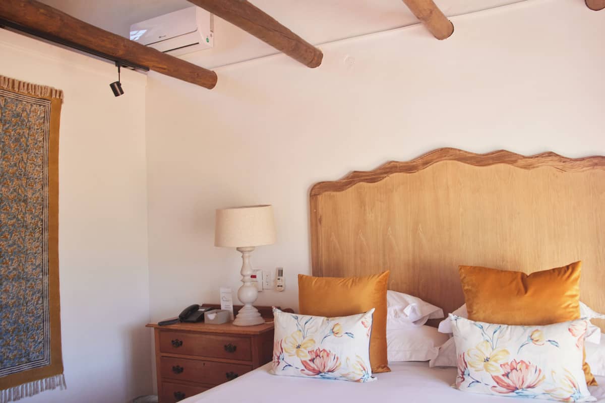 A bedroom with a wooden headboard, a bedside table with a lamp, and floral pillows.
