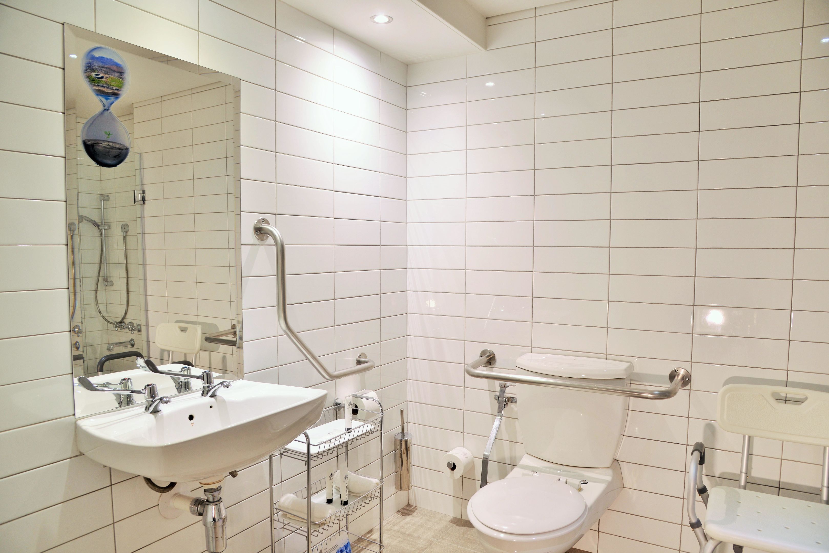 Casa de banho moderna com lavatório branco, espelho e sanita.