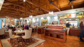 A spacious restaurant with wooden beams, a central bar area, and multiple dining tables.