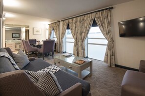 A modern living room with a sofa, armchairs, a glass coffee table, and a flat-screen TV. - The Portswood Hotel (Cape Town)