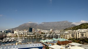 A marina with boats, a cityscape, and a mountain in the background. - The Portswood Hotel (Cape Town)