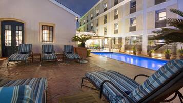 A poolside area with lounge chairs and a pool.