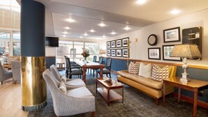 A modern hotel lobby with a large pillar, seating area, and a dining table. - The Portswood Hotel (Cape Town)