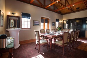 A dining area with a wooden table set for six, surrounded by six chairs with cushioned seats. - The Portswood Hotel (Cape Town)