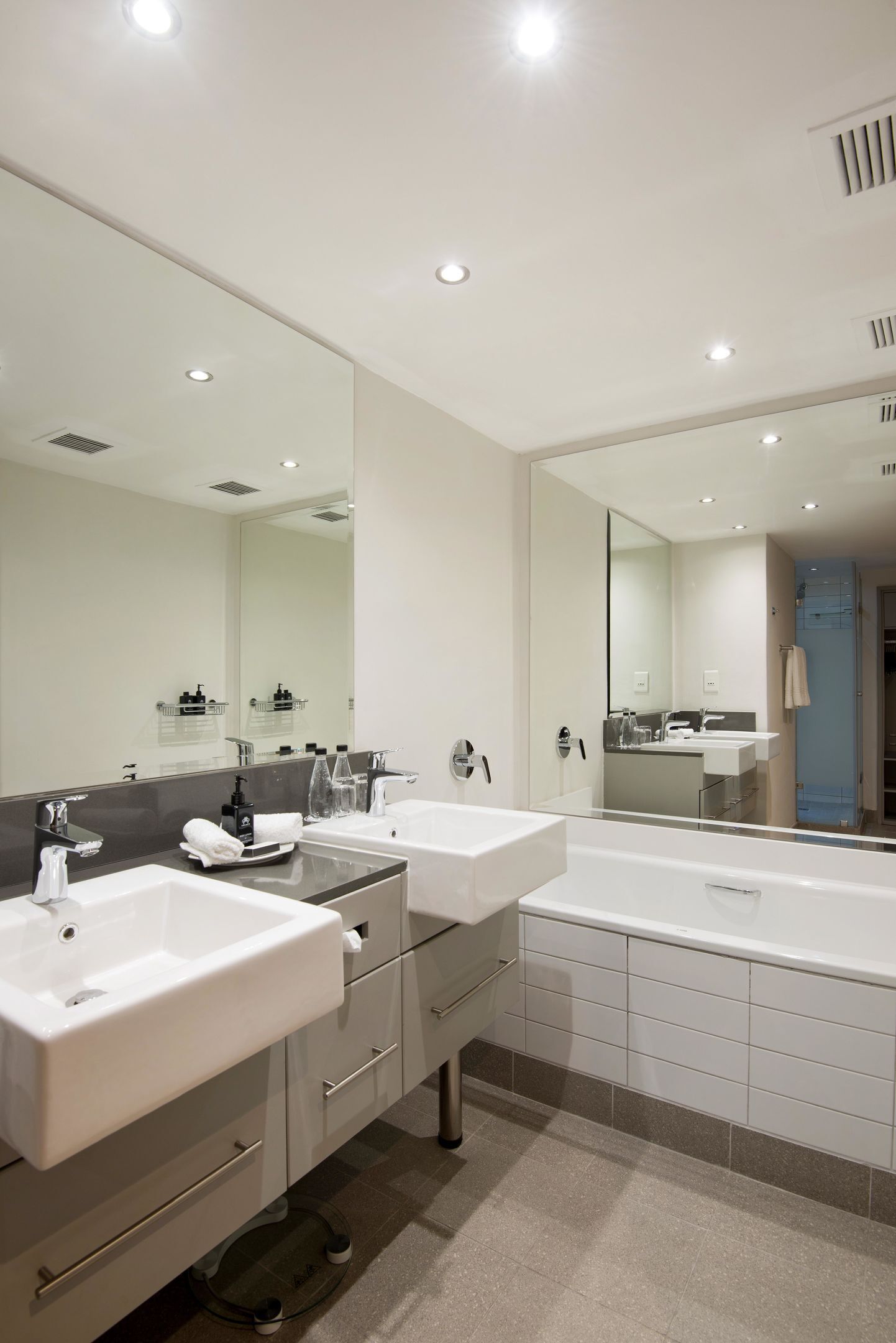 Un baño moderno con dos lavamanos, un espejo grande y una ducha a ras de suelo.