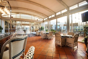 A spacious indoor patio with wicker furniture and large windows.