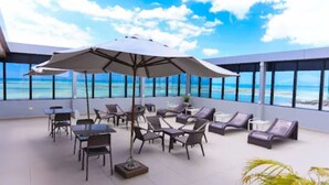 Een terras op het dak met buitenmeubilair, zoals tafels en stoelen, en een grote parasol voor de schaduw.