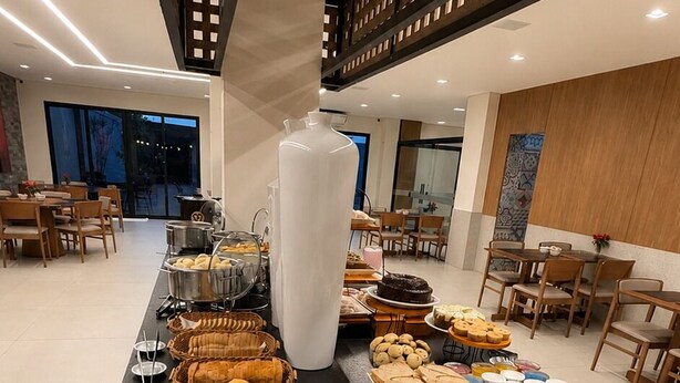 Un bufé con diversos alimentos, un jarrón blanco grande y un ordenador portátil sobre una mesa.