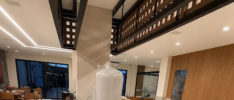 Un bufé con diversos alimentos, un jarrón blanco grande y un ordenador portátil sobre una mesa.