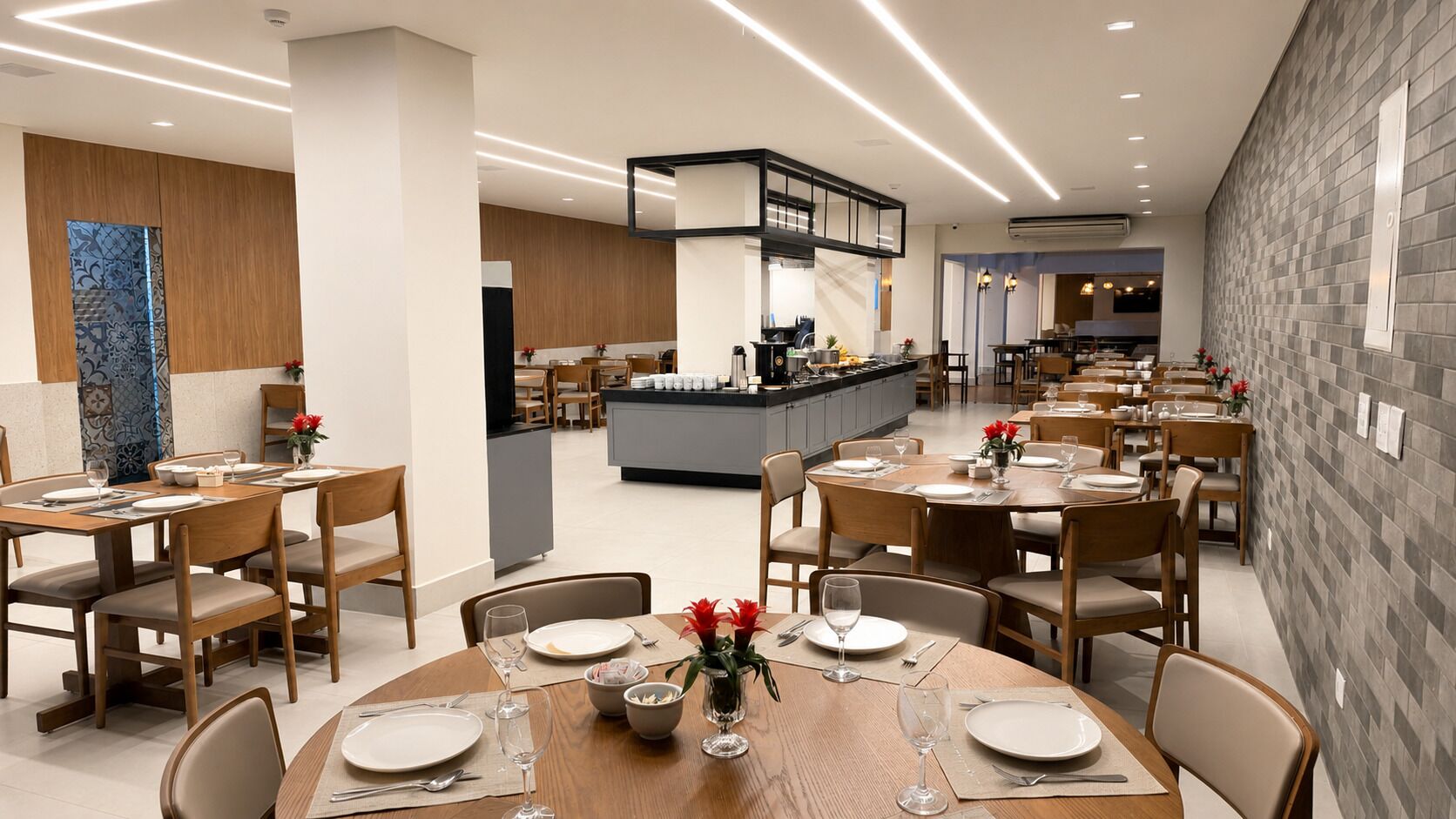 Un comedor moderno con varias mesas y sillas, una zona de cocina central y una pared decorativa.