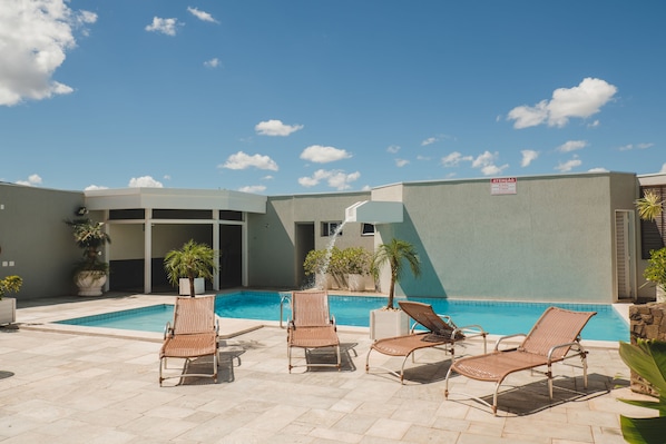 Una piscina al aire libre, sillones reclinables de piscina