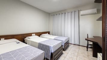 Habitación de hotel con dos camas, un escritorio y un equipo de aire acondicionado.
