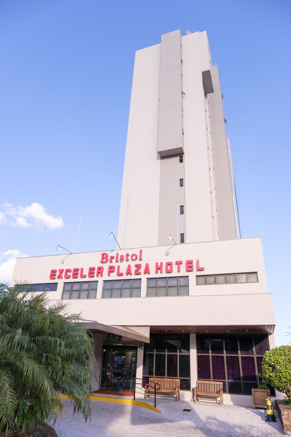 Enter through the glass door to the Bristol Exceller Plaza Hotel, where a flat roof tops a prominent tower structure.