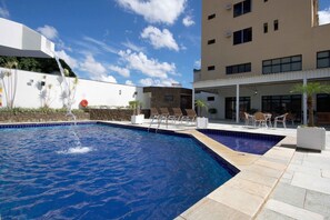 Relax by the rectangular pool with a soothing waterfall feature, surrounded by comfortable seating and large windows.