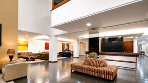 Un vestíbulo amplio con techo alto, un sofá grande y una mesa de recepción.