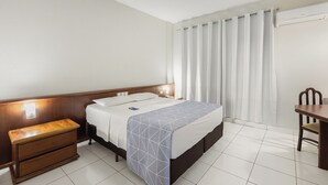 Una habitación de hotel con cama, mesita de noche y escritorio con silla.