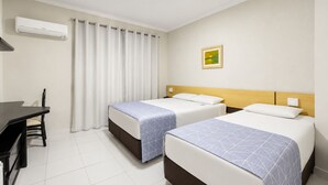 Una habitación de hotel con dos camas, un escritorio y una ventana con cortinas.