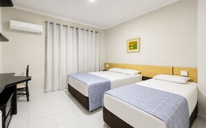 Una habitación de hotel con dos camas, un escritorio y una ventana con cortinas.