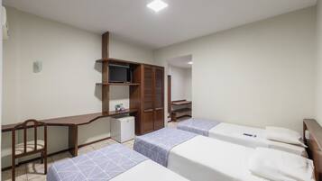A hotel room with a desk, two beds, a wardrobe, and a television.