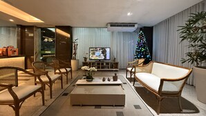 A modern living room with a flat-screen TV, a Christmas tree, and a reception desk.