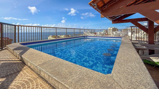 A rooftop pool with a clear view of the ocean and cityscape.