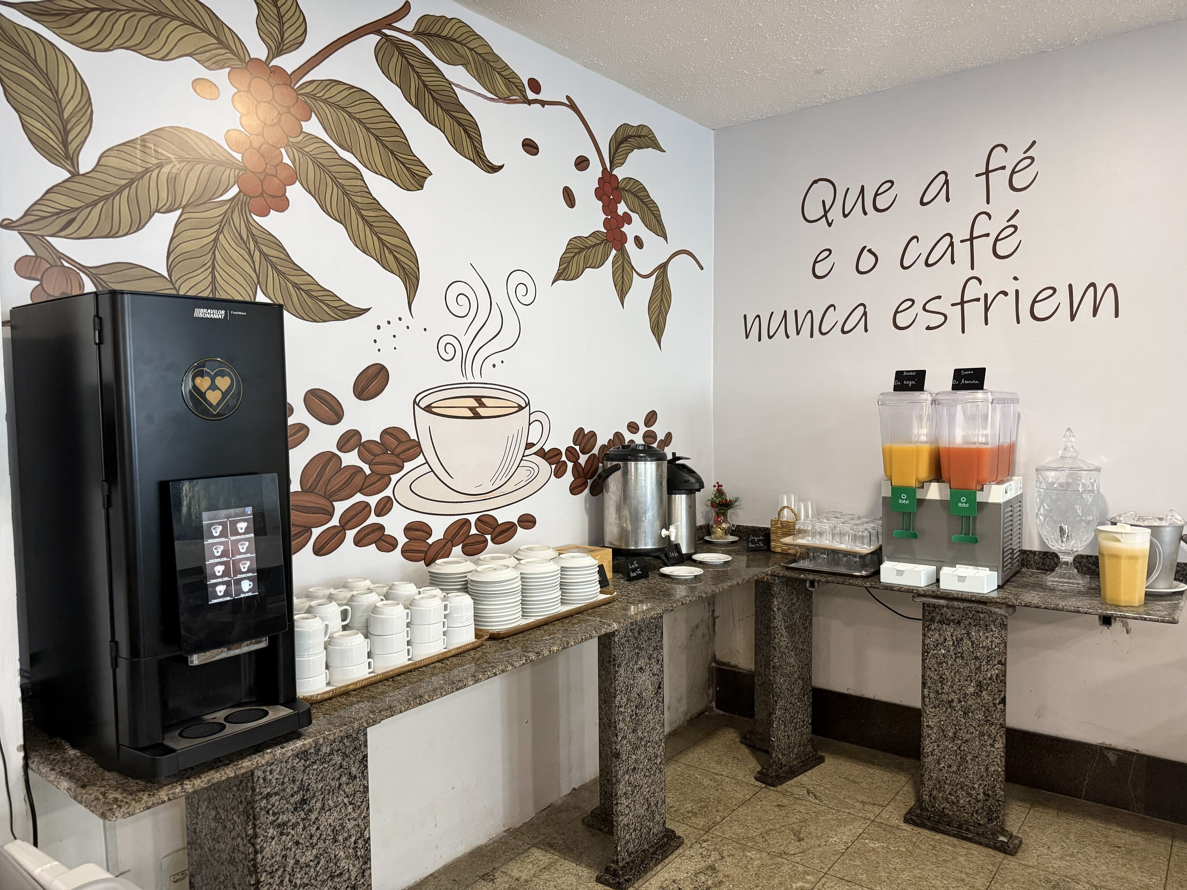 Un espace dédié au café, comprenant une machine à café, des tasses et une fresque murale.