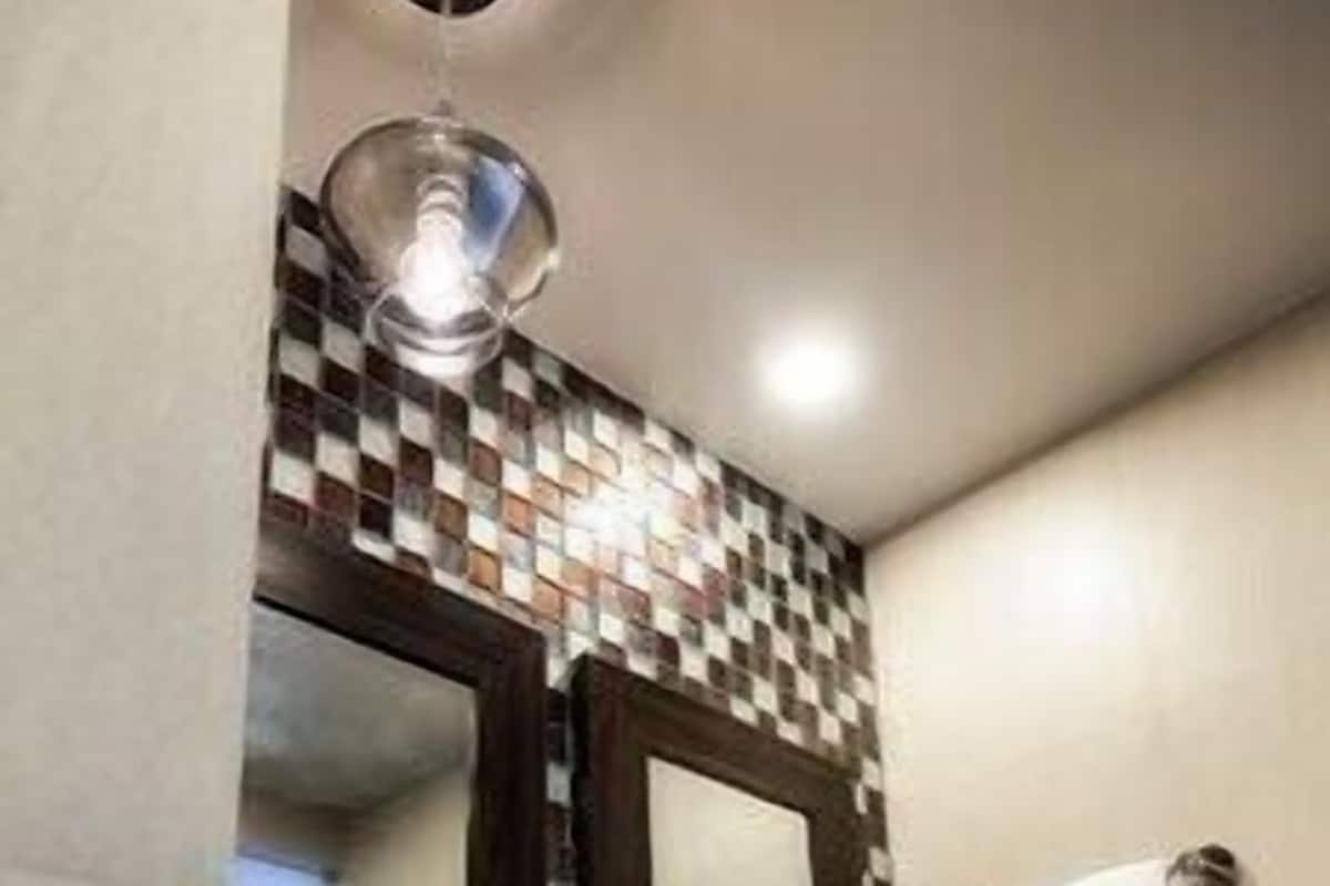 A bathroom with a checkered tile backsplash, a white sink, two mirrors, and a towel rack with two towels.