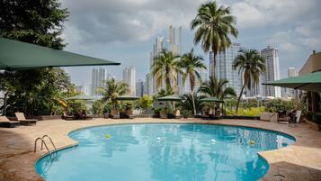 Una piscina al aire libre, sombrillas, sillones reclinables de piscina
