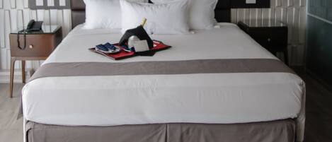 Una habitación de hotel moderna con una cama grande, una mesita de noche con lámpara y un aplique de pared.